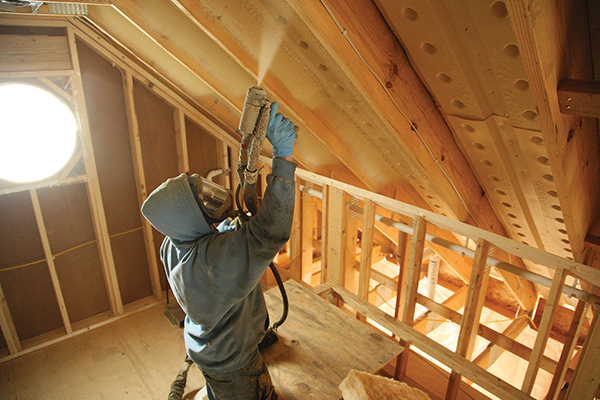 在阁楼上喷涂泡沫发泡的男人